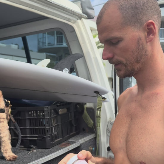 Surfer applying Glass Wholefoods Tallow Zinc Sun Balm before heading to the beach