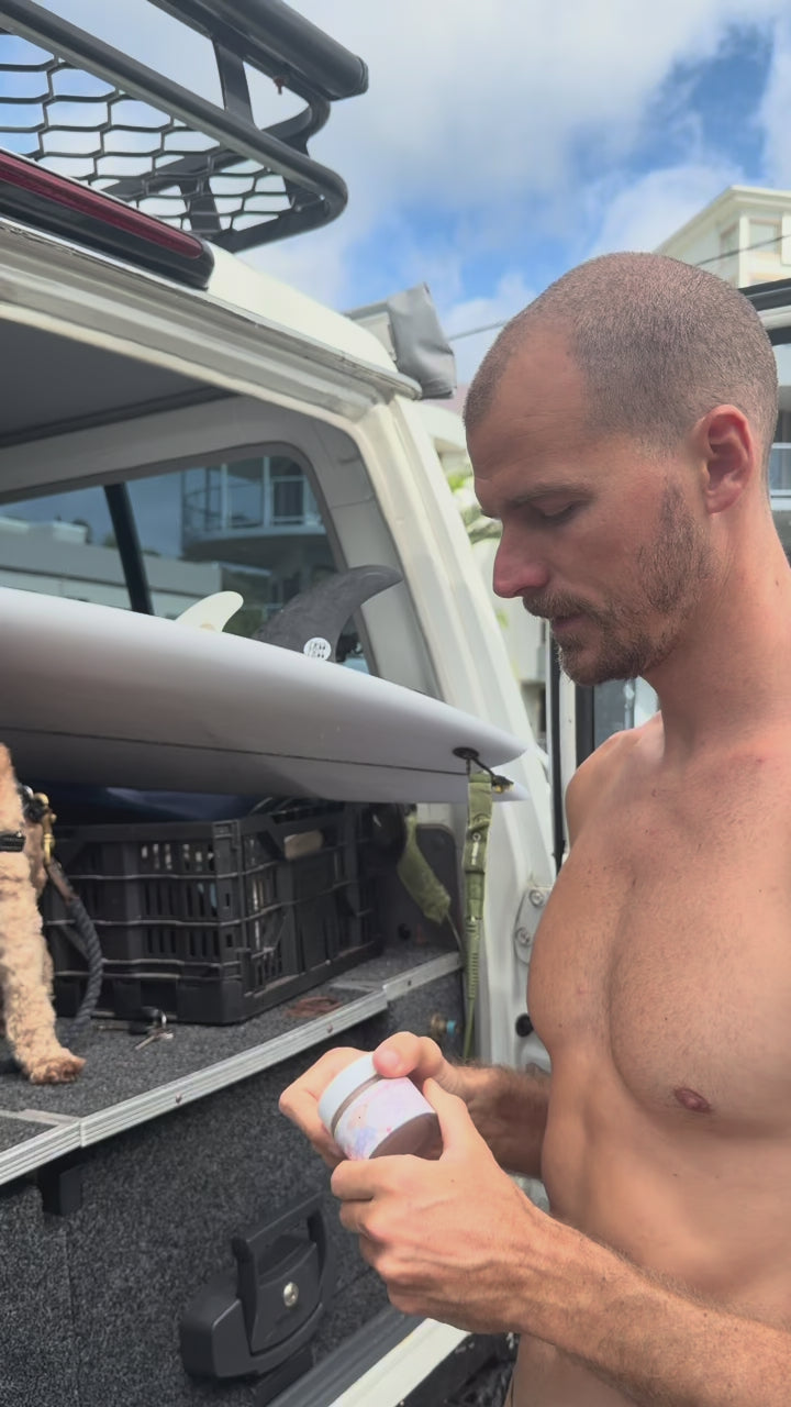 Surfer applying Glass Wholefoods Tallow Zinc Sun Balm before heading to the beach